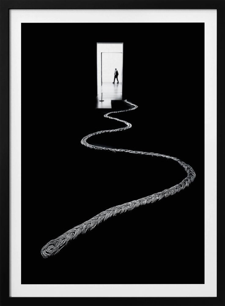 A high-contrast, black and white photograph of a thick, silver, braided rope winding across a black floor, leading towards a brightly lit doorway in the distance where a silhouetted man is walking away. Wall Art