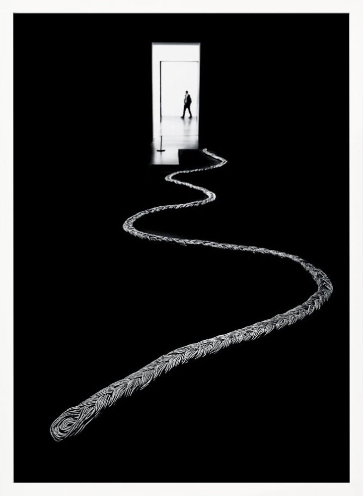 A high-contrast, black and white photograph of a thick, silver, braided rope winding across a black floor, leading towards a brightly lit doorway in the distance where a silhouetted man is walking away. Wall Art