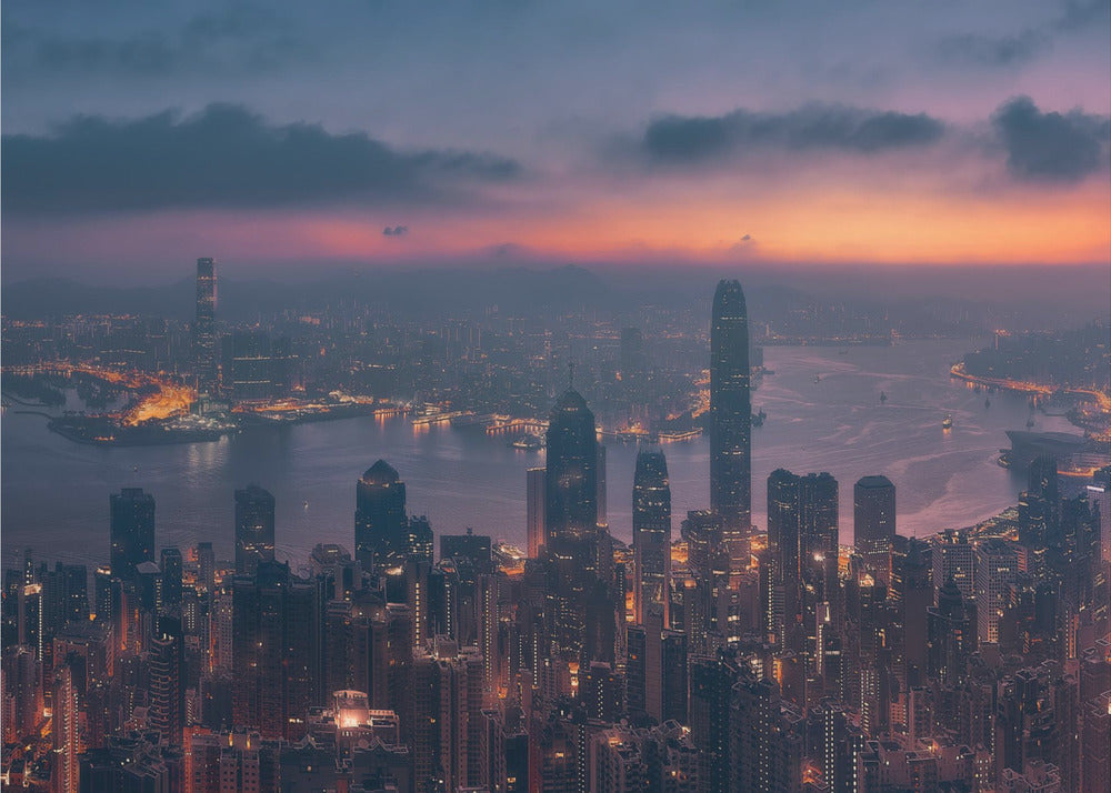 An aerial photograph of a sprawling city skyline at dusk, likely Hong Kong, with countless illuminated skyscrapers. The sky above transitions from a warm orange glow at the horizon to a deep purple, with dark clouds overhead. The city lights cast a golden reflection on the water of the harbor. The entire image is presented within a silver-colored frame. Poster