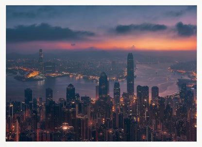 An aerial photograph of a sprawling city skyline at dusk, likely Hong Kong, with countless illuminated skyscrapers. The sky above transitions from a warm orange glow at the horizon to a deep purple, with dark clouds overhead. The city lights cast a golden reflection on the water of the harbor. The entire image is presented within a silver-colored frame. Poster