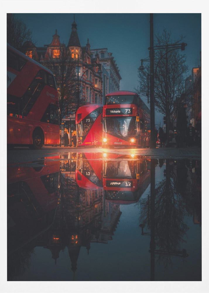 A moody, low-angle photograph of a wet London street at dusk, with a vibrant red double-decker bus reflected perfectly in a large puddle in the foreground. Print