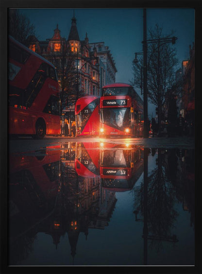 A moody, low-angle photograph of a wet London street at dusk, with a vibrant red double-decker bus reflected perfectly in a large puddle in the foreground. Print