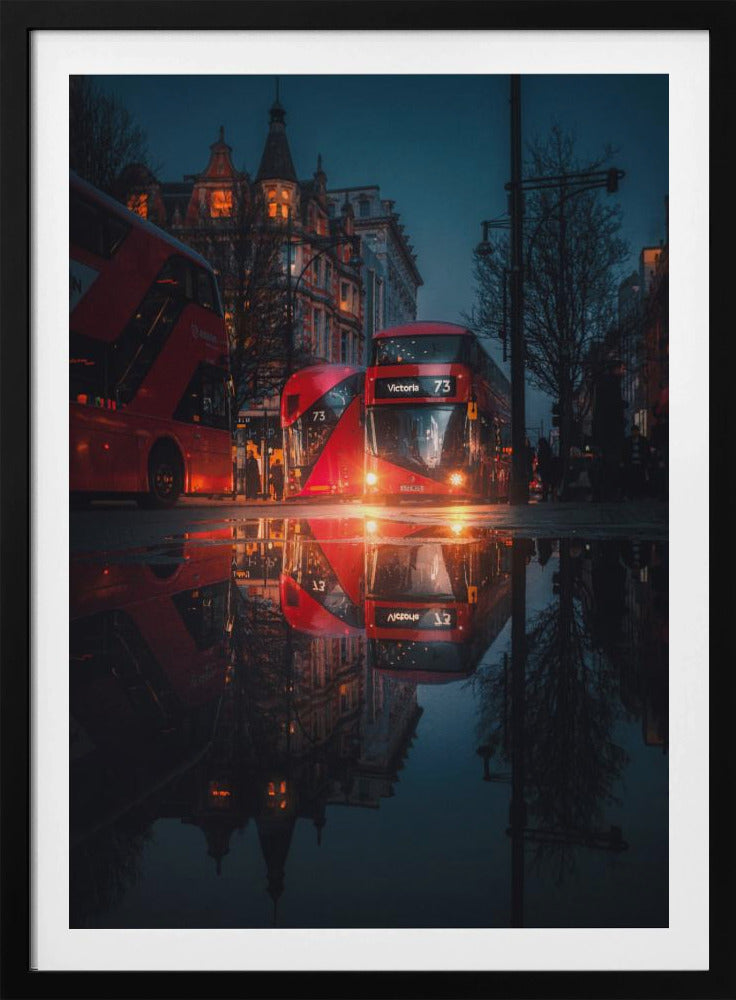 A moody, low-angle photograph of a wet London street at dusk, with a vibrant red double-decker bus reflected perfectly in a large puddle in the foreground. Print