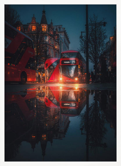 A moody, low-angle photograph of a wet London street at dusk, with a vibrant red double-decker bus reflected perfectly in a large puddle in the foreground. Print