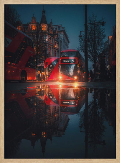 A moody, low-angle photograph of a wet London street at dusk, with a vibrant red double-decker bus reflected perfectly in a large puddle in the foreground. Print