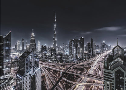 A striking black and white aerial photograph of the Dubai skyline at night, captured in a silver frame. The Burj Khalifa stands tall in the background, while a complex web of illuminated highway overpasses and light trails from traffic fills the foreground, creating a dynamic and futuristic cityscape. Print