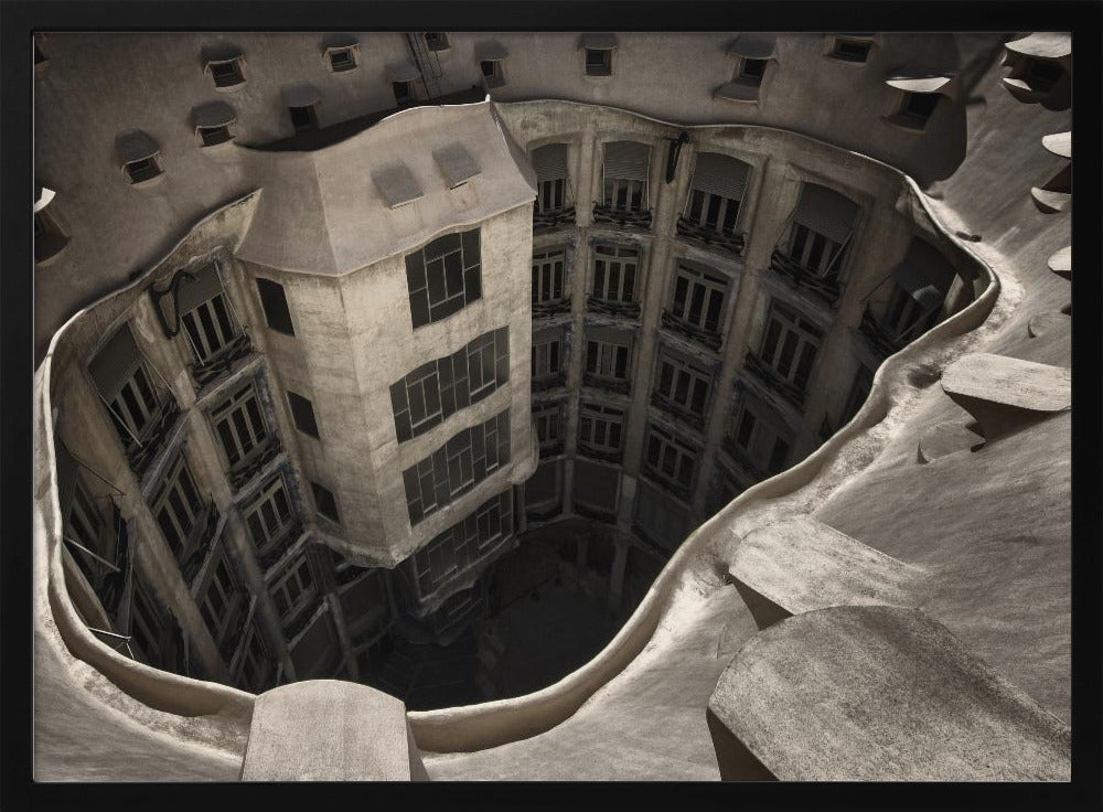 A surreal, high-angle photograph looking down into the distorted, cavernous courtyard of a building. The walls and windows appear to melt and curve inwards towards a dark void, creating a powerful optical illusion. The image has a muted, sepia-toned color palette and is presented in a silver frame. Wall Art
