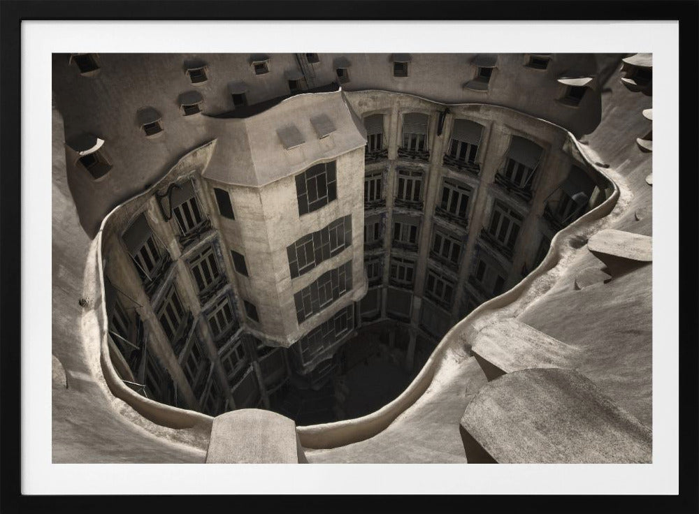 A surreal, high-angle photograph looking down into the distorted, cavernous courtyard of a building. The walls and windows appear to melt and curve inwards towards a dark void, creating a powerful optical illusion. The image has a muted, sepia-toned color palette and is presented in a silver frame. Wall Art