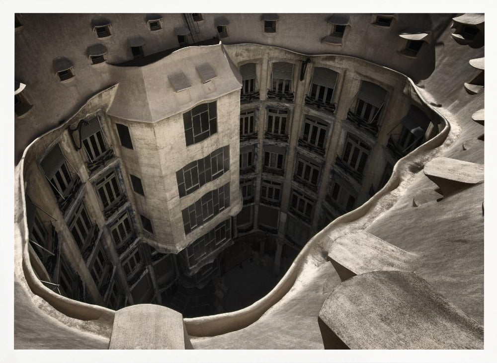A surreal, high-angle photograph looking down into the distorted, cavernous courtyard of a building. The walls and windows appear to melt and curve inwards towards a dark void, creating a powerful optical illusion. The image has a muted, sepia-toned color palette and is presented in a silver frame. Wall Art