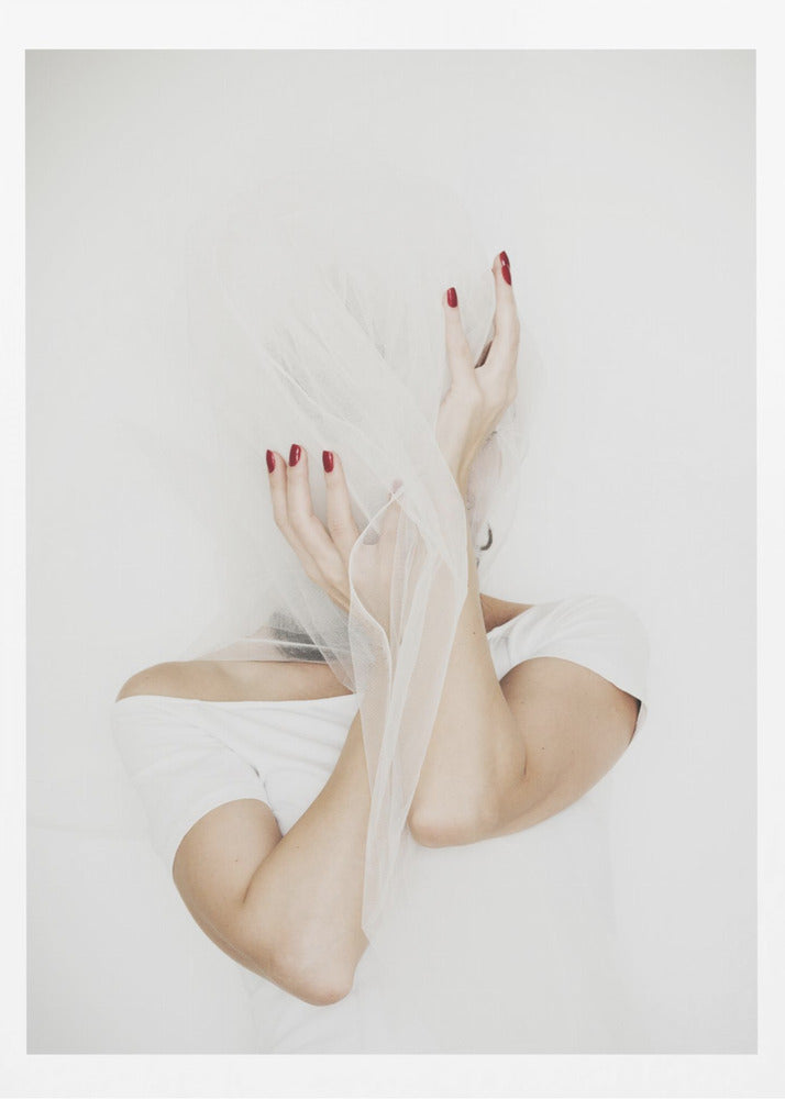 A minimalist photograph of a person in a white t-shirt against a white background, their face hidden by a sheer white veil. Their hands, adorned with bright red nail polish, frame the veiled face in an expressive pose. Wall Art