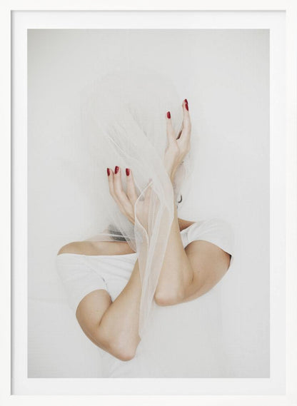 A minimalist photograph of a person in a white t-shirt against a white background, their face hidden by a sheer white veil. Their hands, adorned with bright red nail polish, frame the veiled face in an expressive pose. Wall Art