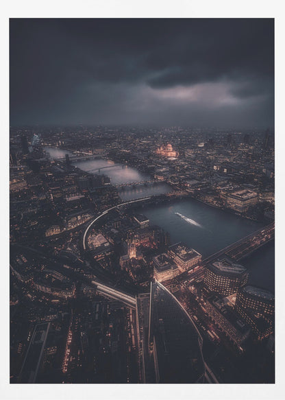 An aerial photograph of London at night from a high vantage point, overlooking the winding River Thames illuminated by the golden glow of city lights under a dark, dramatic, and cloudy sky. Wall Art