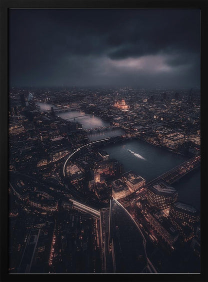 An aerial photograph of London at night from a high vantage point, overlooking the winding River Thames illuminated by the golden glow of city lights under a dark, dramatic, and cloudy sky. Wall Art