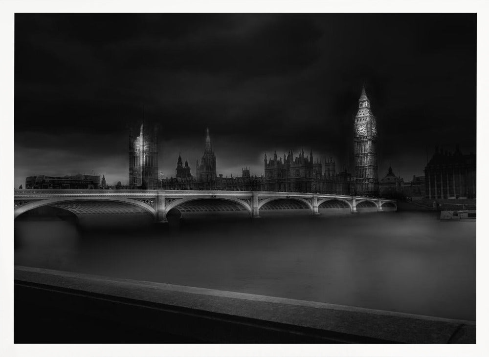 A moody, atmospheric black and white photograph of the Houses of Parliament and Big Ben in London, viewed from across the River Thames. The iconic buildings are softly illuminated against a dark, dramatic sky, with Westminster Bridge arching over the dark, smooth water in the foreground. The image is presented within a silver-colored frame. Artwork