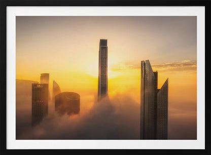 A framed photograph of a modern city skyline with skyscrapers emerging from a thick layer of clouds at sunrise, creating a dramatic and ethereal scene against a golden sky. Wall Art