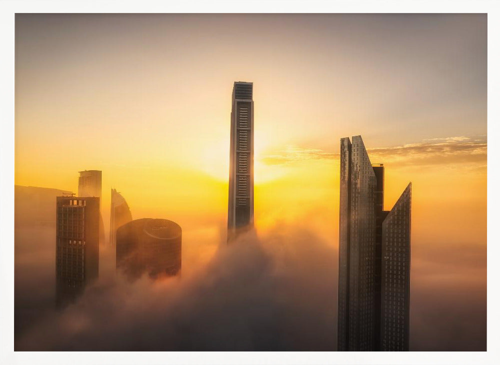 A framed photograph of a modern city skyline with skyscrapers emerging from a thick layer of clouds at sunrise, creating a dramatic and ethereal scene against a golden sky. Wall Art