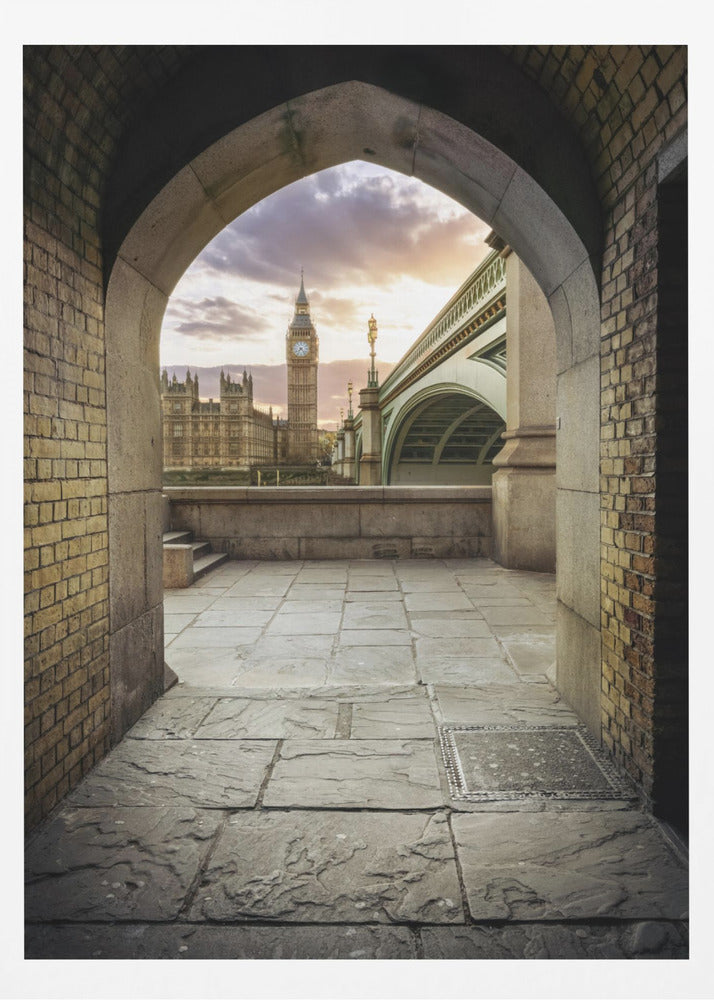 A scenic view of London's Big Ben clock tower and the Houses of Parliament as seen through a weathered stone archway. The foreground features a stone-paved walkway, and the background shows the iconic landmarks against a cloudy sunset sky with hues of purple and orange. Poster