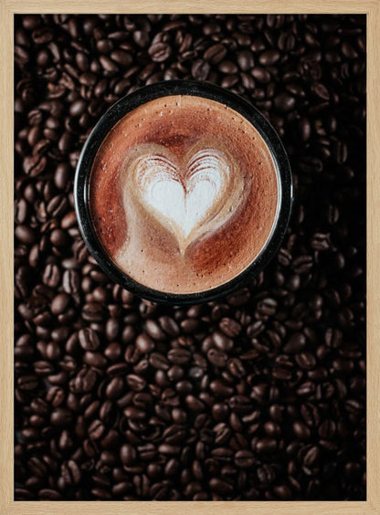 A top-down view of a cappuccino in a black mug with a white heart-shaped foam art design, placed on a bed of dark roasted coffee beans. Artwork