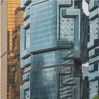 A framed close-up photograph of modern architecture, featuring a golden grid-patterned skyscraper next to a complex blue glass building with jutting levels and distorted reflections. Wall Art
