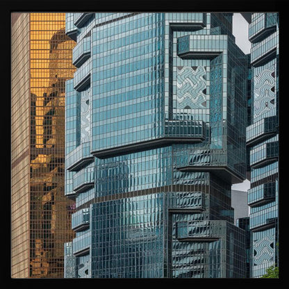 A framed close-up photograph of modern architecture, featuring a golden grid-patterned skyscraper next to a complex blue glass building with jutting levels and distorted reflections. Wall Art