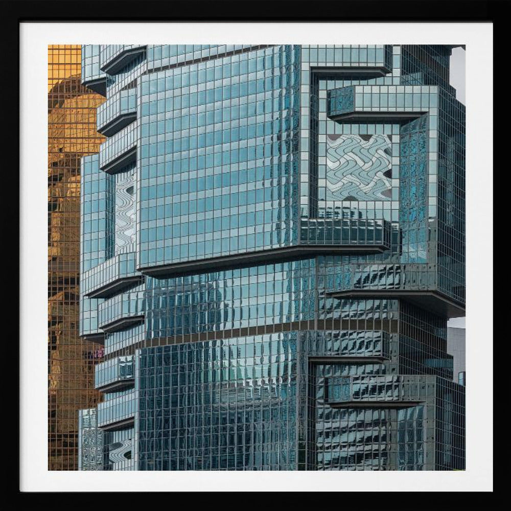 A framed close-up photograph of modern architecture, featuring a golden grid-patterned skyscraper next to a complex blue glass building with jutting levels and distorted reflections. Wall Art