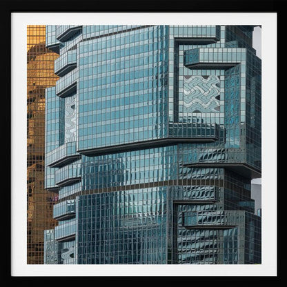 A framed close-up photograph of modern architecture, featuring a golden grid-patterned skyscraper next to a complex blue glass building with jutting levels and distorted reflections. Wall Art