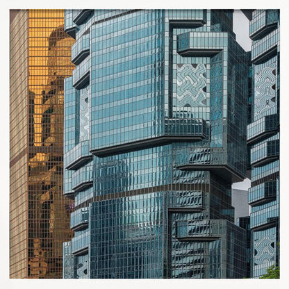 A framed close-up photograph of modern architecture, featuring a golden grid-patterned skyscraper next to a complex blue glass building with jutting levels and distorted reflections. Wall Art