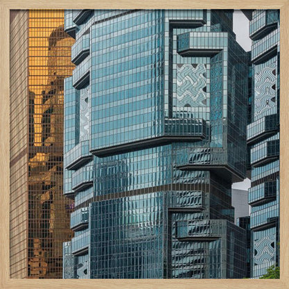 A framed close-up photograph of modern architecture, featuring a golden grid-patterned skyscraper next to a complex blue glass building with jutting levels and distorted reflections. Wall Art