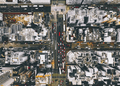 A framed, top-down aerial photo of a dense city grid. The monochromatic scene of white rooftops and dark streets is punctuated by the red and white cars creating lines of traffic below. Decor