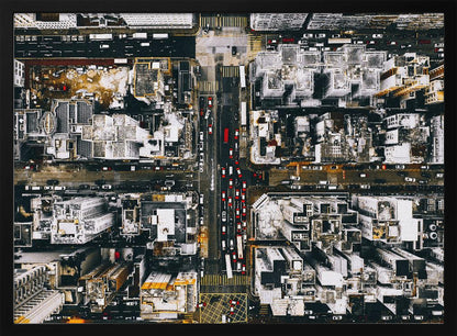 A framed, top-down aerial photo of a dense city grid. The monochromatic scene of white rooftops and dark streets is punctuated by the red and white cars creating lines of traffic below. Decor