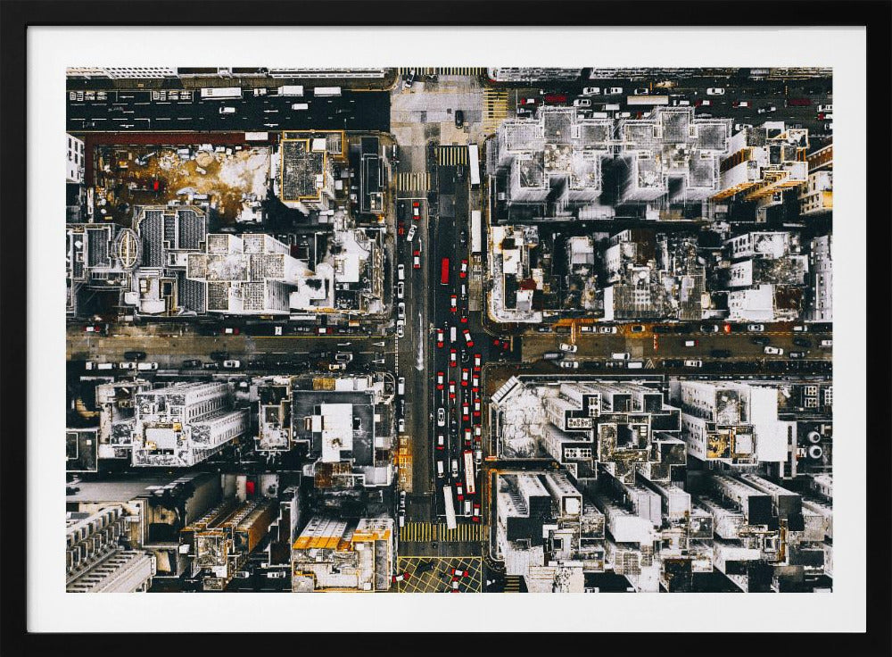 A framed, top-down aerial photo of a dense city grid. The monochromatic scene of white rooftops and dark streets is punctuated by the red and white cars creating lines of traffic below. Decor