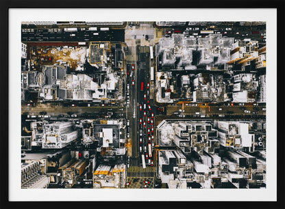 A framed, top-down aerial photo of a dense city grid. The monochromatic scene of white rooftops and dark streets is punctuated by the red and white cars creating lines of traffic below. Decor