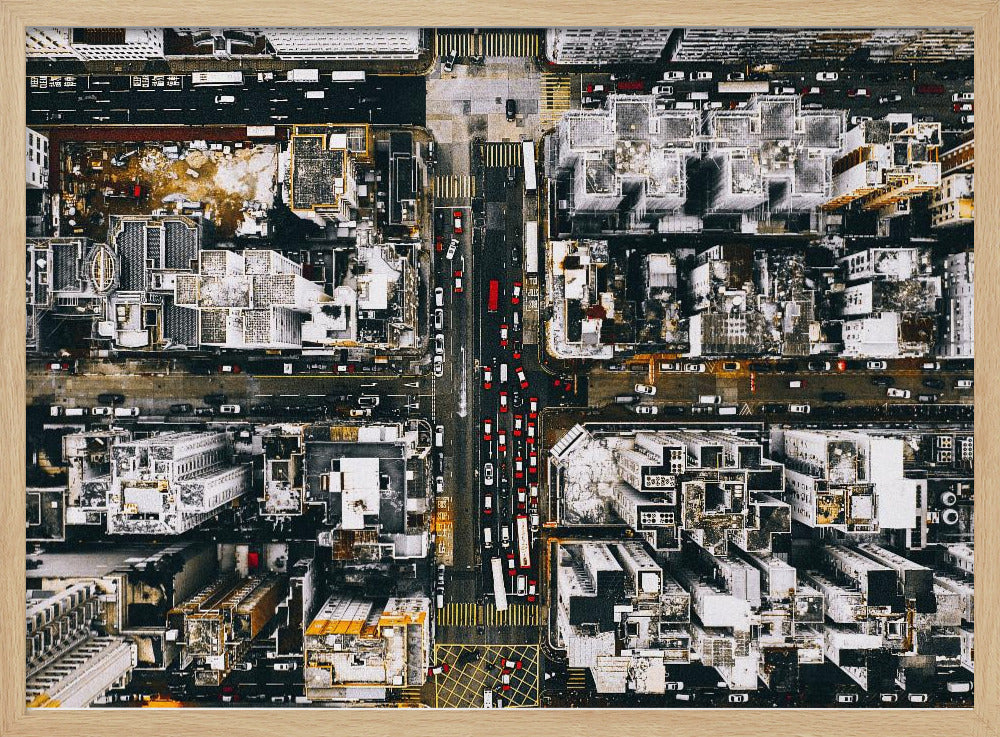 A framed, top-down aerial photo of a dense city grid. The monochromatic scene of white rooftops and dark streets is punctuated by the red and white cars creating lines of traffic below. Decor