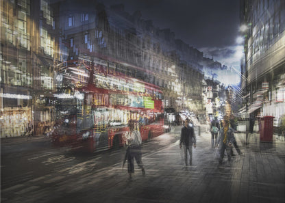 A long-exposure, artistic photograph of a busy London street at night. The motion of a red double-decker bus and pedestrians creates a blurred, ghost-like effect, capturing the vibrant energy of the city. The scene is illuminated by streetlights and building windows, all set within a silver frame. Artwork