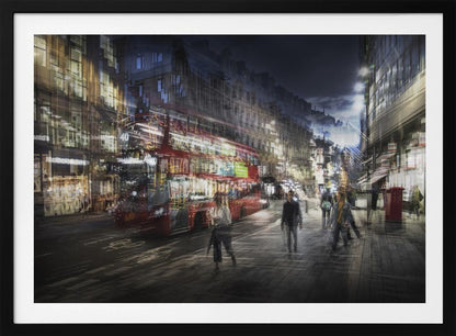 A long-exposure, artistic photograph of a busy London street at night. The motion of a red double-decker bus and pedestrians creates a blurred, ghost-like effect, capturing the vibrant energy of the city. The scene is illuminated by streetlights and building windows, all set within a silver frame. Artwork
