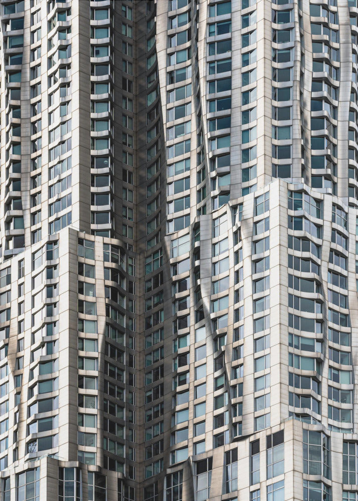 A close-up photograph of the facade of a modern skyscraper with an undulating, wave-like metallic exterior. The building is filled with windows that reflect the light, creating a dynamic pattern of highlights and shadows, all captured within a black frame. Print