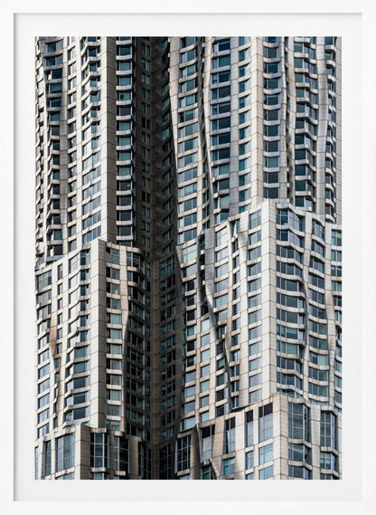 A close-up photograph of the facade of a modern skyscraper with an undulating, wave-like metallic exterior. The building is filled with windows that reflect the light, creating a dynamic pattern of highlights and shadows, all captured within a black frame. Print