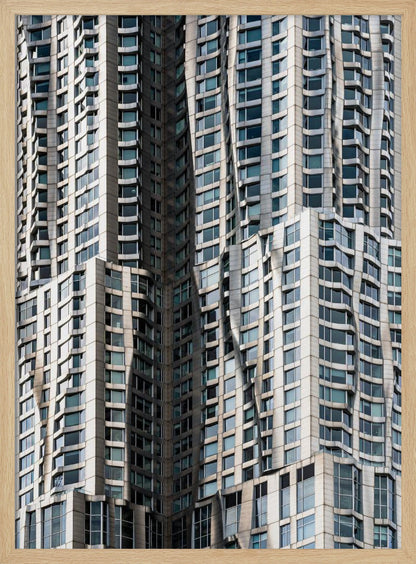 A close-up photograph of the facade of a modern skyscraper with an undulating, wave-like metallic exterior. The building is filled with windows that reflect the light, creating a dynamic pattern of highlights and shadows, all captured within a black frame. Print