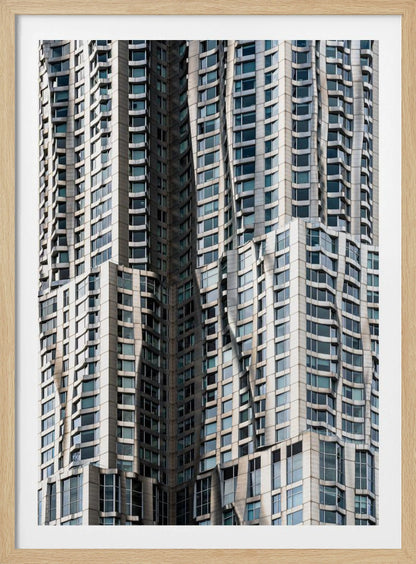A close-up photograph of the facade of a modern skyscraper with an undulating, wave-like metallic exterior. The building is filled with windows that reflect the light, creating a dynamic pattern of highlights and shadows, all captured within a black frame. Print