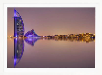 A framed panoramic night photograph of the Dubai skyline featuring the Burj Al Arab hotel lit up in brilliant purple. The city lights and architecture are perfectly reflected in the calm water in the foreground, all under a hazy, dusky sky. Poster