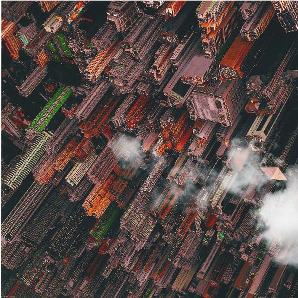 A dramatic, high-angle aerial photograph looking straight down into a super-dense, futuristic cityscape with towering skyscrapers packed together, featuring pops of orange and green among the dark buildings. Wisps of clouds float between the towers, and the image is presented in a light wood frame. Print