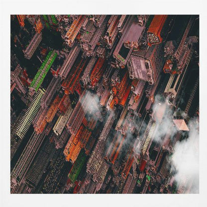 A dramatic, high-angle aerial photograph looking straight down into a super-dense, futuristic cityscape with towering skyscrapers packed together, featuring pops of orange and green among the dark buildings. Wisps of clouds float between the towers, and the image is presented in a light wood frame. Print