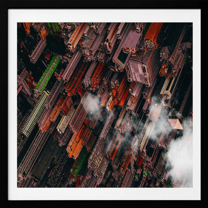 A dramatic, high-angle aerial photograph looking straight down into a super-dense, futuristic cityscape with towering skyscrapers packed together, featuring pops of orange and green among the dark buildings. Wisps of clouds float between the towers, and the image is presented in a light wood frame. Print