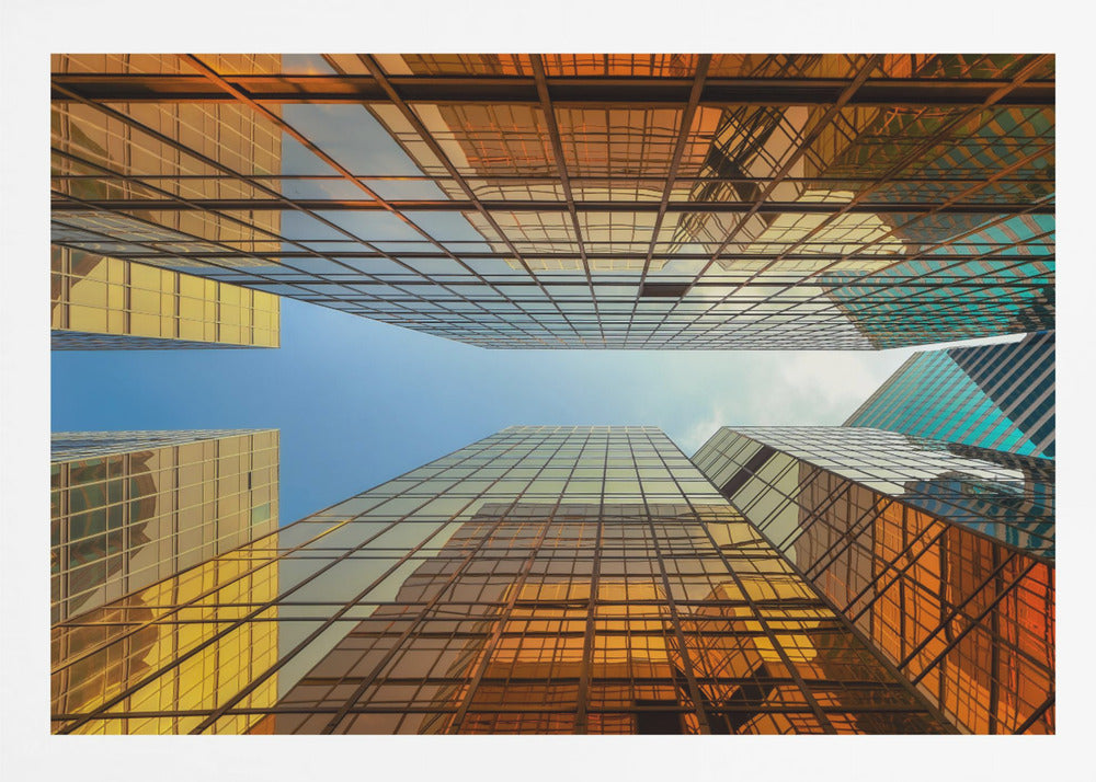 A low-angle, upward view of modern skyscrapers with golden reflective glass windows, creating a geometric pattern against a narrow strip of clear blue sky. Decor