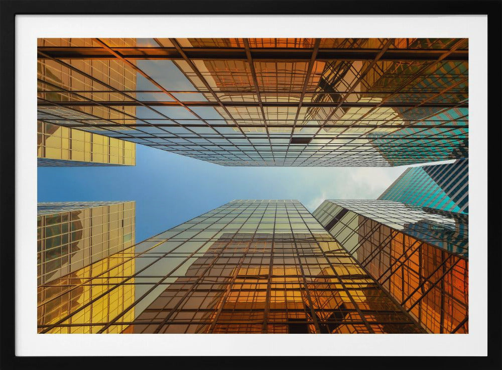 A low-angle, upward view of modern skyscrapers with golden reflective glass windows, creating a geometric pattern against a narrow strip of clear blue sky. Decor