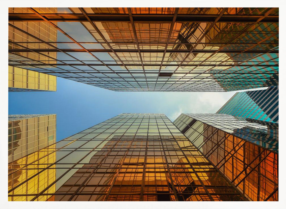 A low-angle, upward view of modern skyscrapers with golden reflective glass windows, creating a geometric pattern against a narrow strip of clear blue sky. Decor