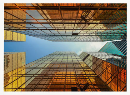 A low-angle, upward view of modern skyscrapers with golden reflective glass windows, creating a geometric pattern against a narrow strip of clear blue sky. Decor