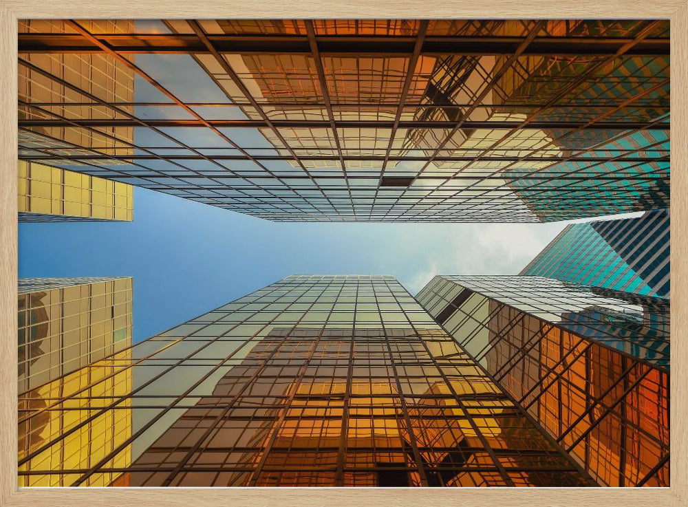 A low-angle, upward view of modern skyscrapers with golden reflective glass windows, creating a geometric pattern against a narrow strip of clear blue sky. Decor
