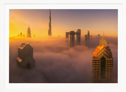 An aerial photograph of the Dubai skyline shrouded in a thick blanket of fog at sunrise. The warm golden light illuminates the tops of several skyscrapers, including the Burj Khalifa, which pierce through the clouds creating a dreamlike and majestic scene. Print