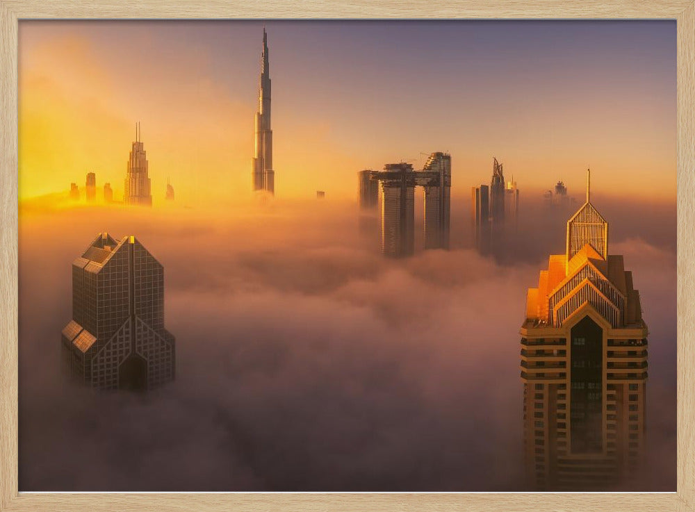 An aerial photograph of the Dubai skyline shrouded in a thick blanket of fog at sunrise. The warm golden light illuminates the tops of several skyscrapers, including the Burj Khalifa, which pierce through the clouds creating a dreamlike and majestic scene. Print